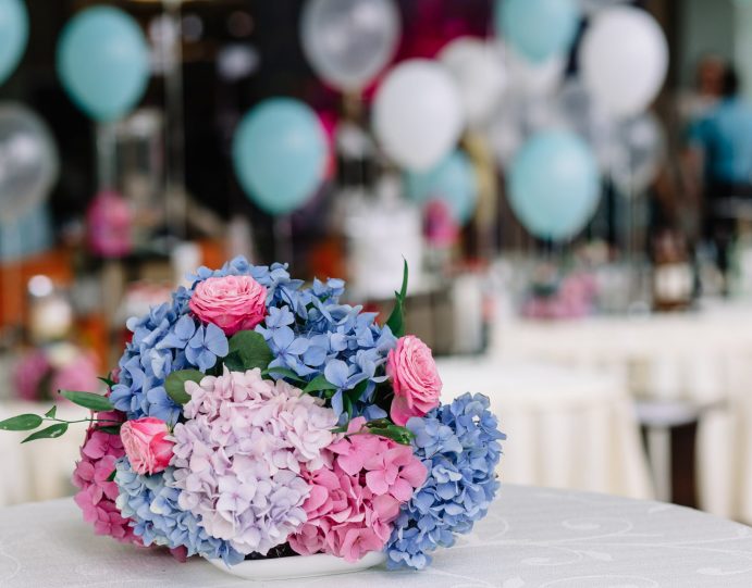 Bouquet of pink and blue hydrangeas and roses lies on white table